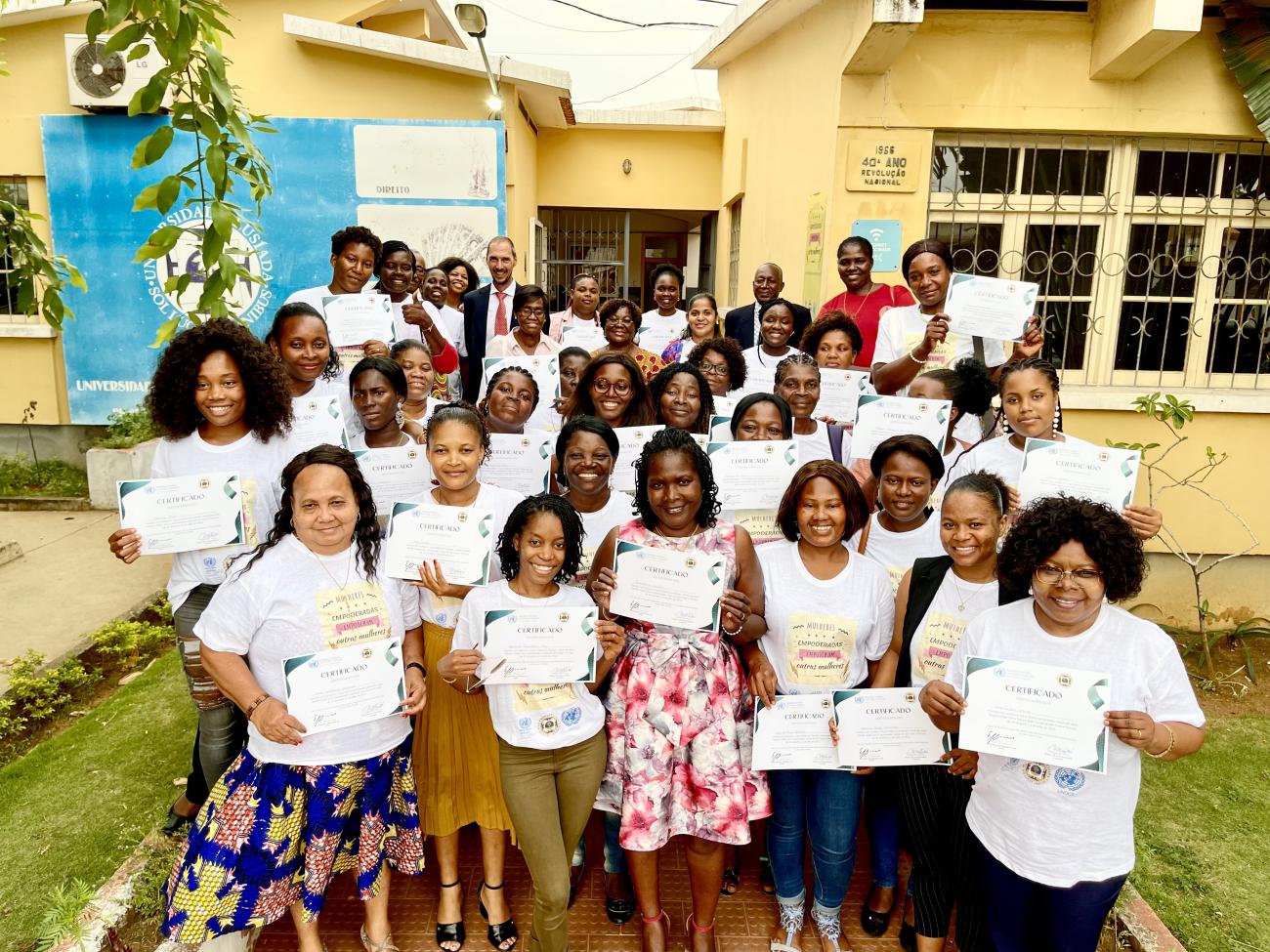 A large group of women hold up certificates