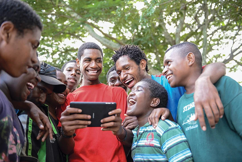 A group of young people gather around a digital tablet