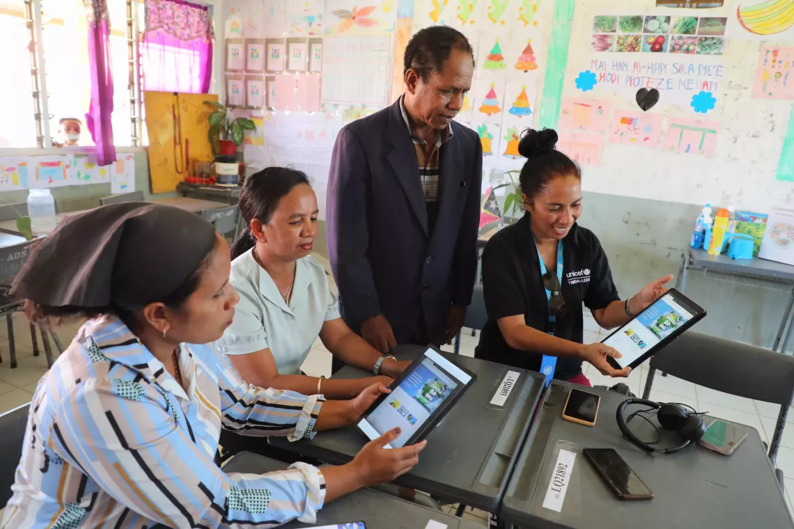 A group of teachers sharing each others' tablets.