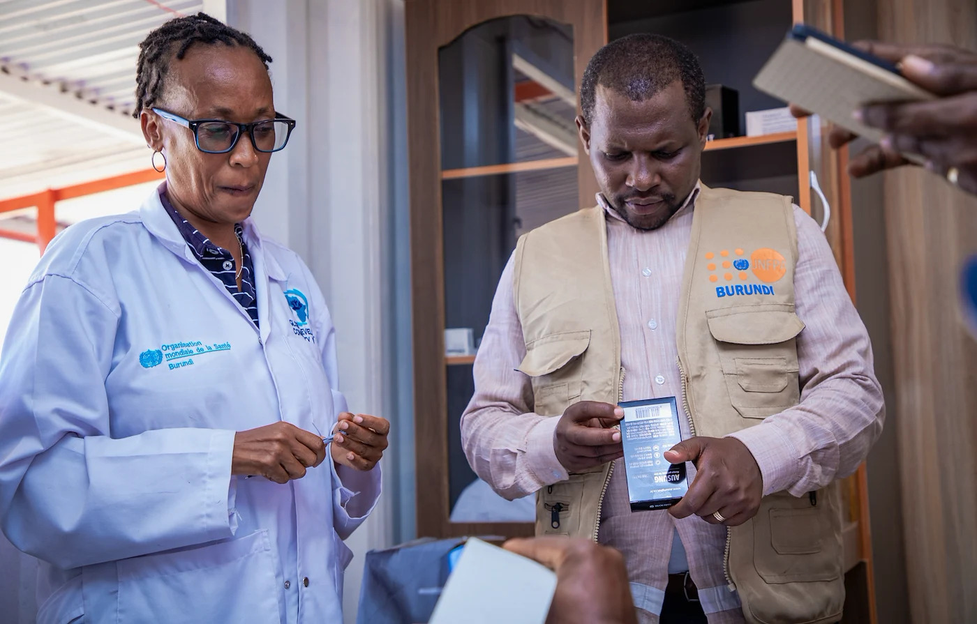 A female and male health worker look at a box of medications in Burundi.