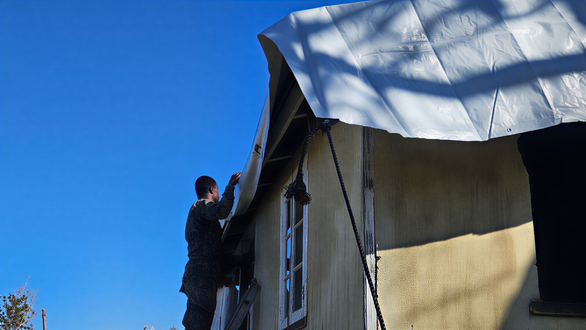 A soldier in Jamaica installs a tarpaulin.