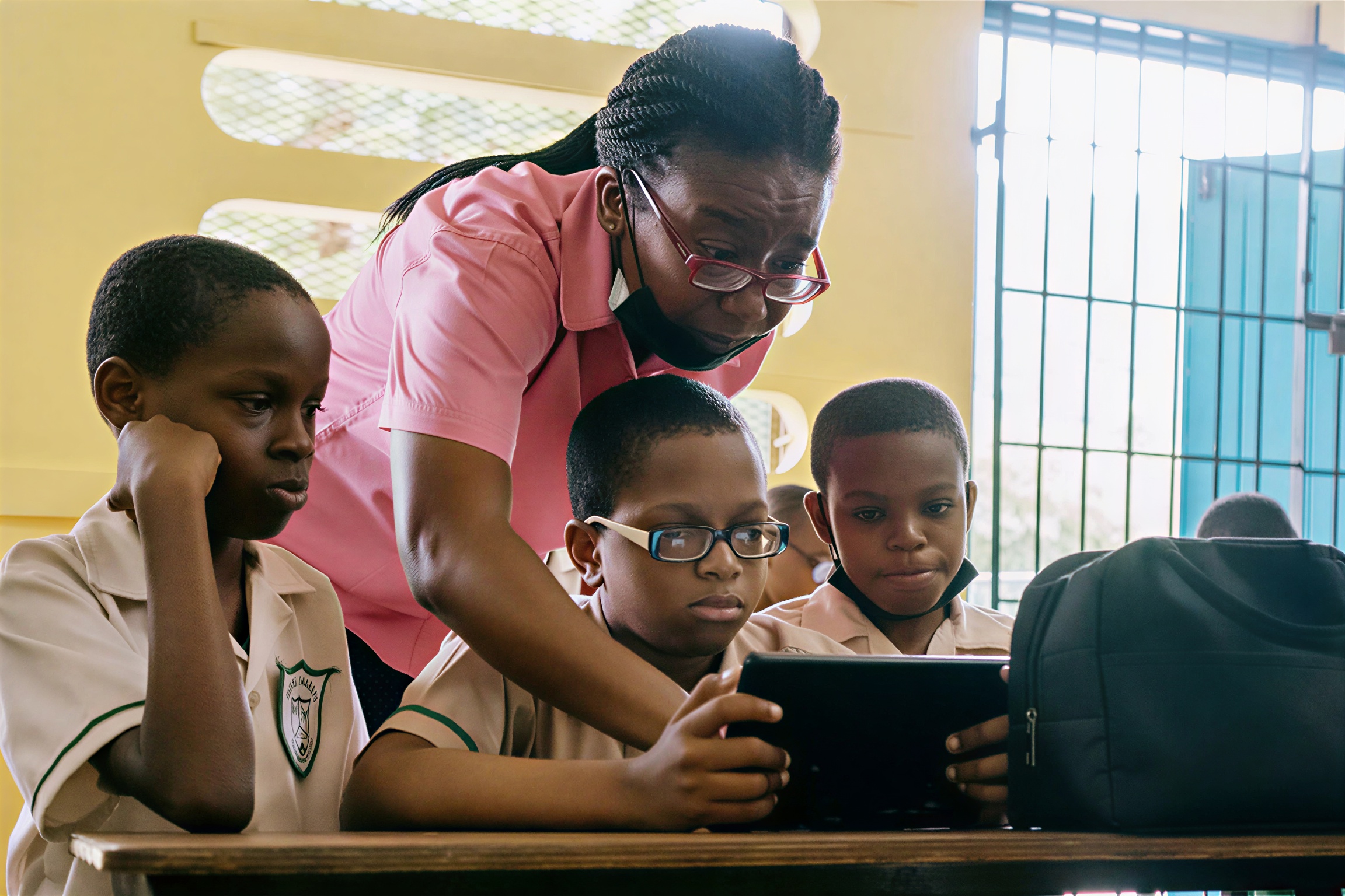 A teacher in Jamaica helps her students as they use a tablet.