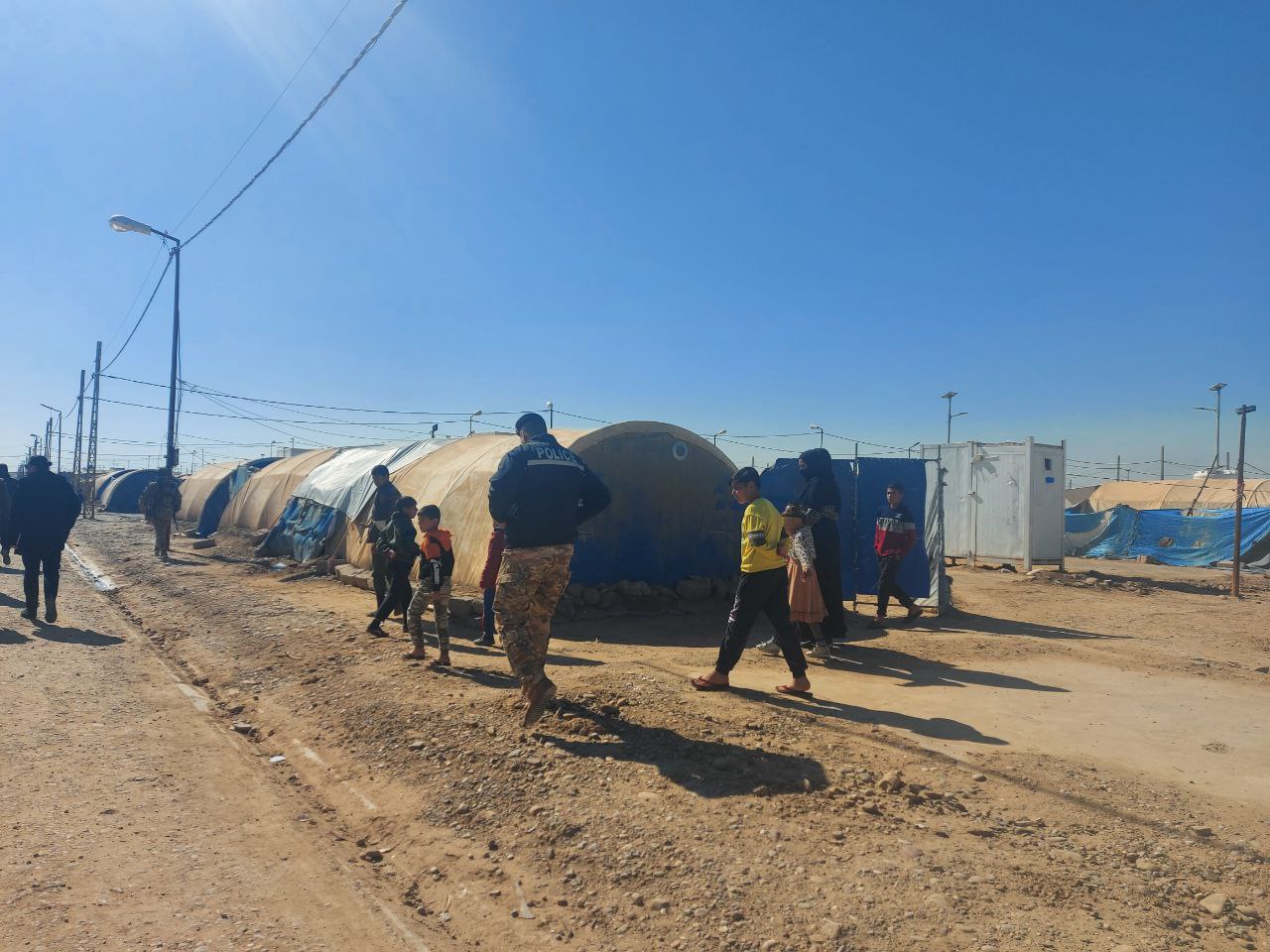 people walking through a displacement camp 