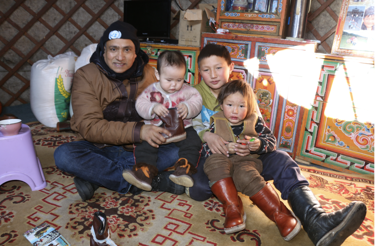 Man sits on carpet with three children 