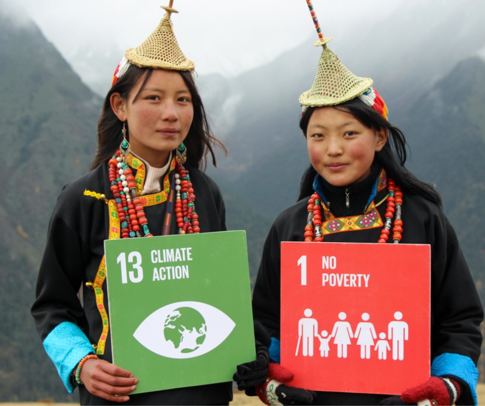 Two young girls hold the sustainable development goals.