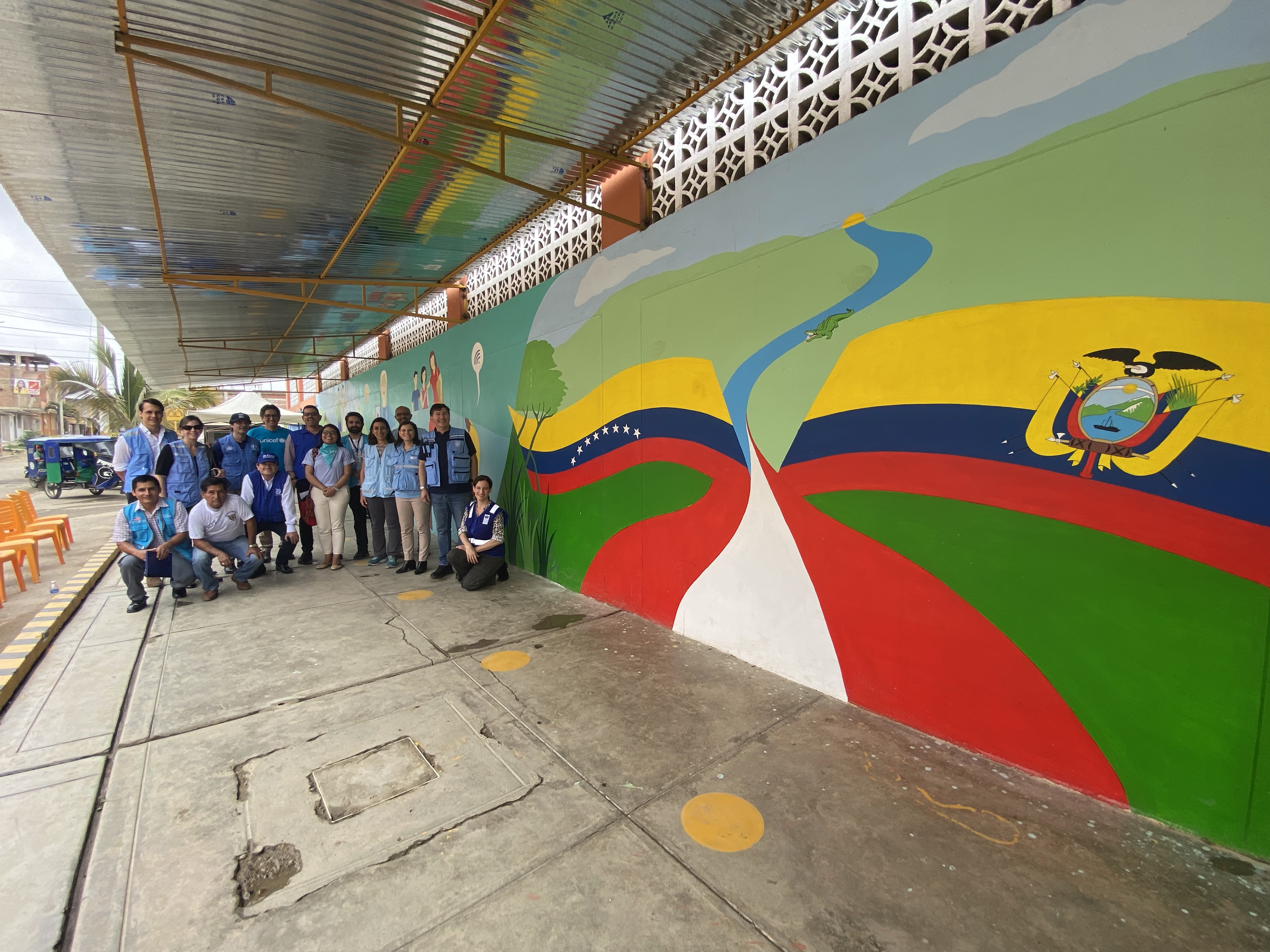 A group of people pose next to a painted wall 