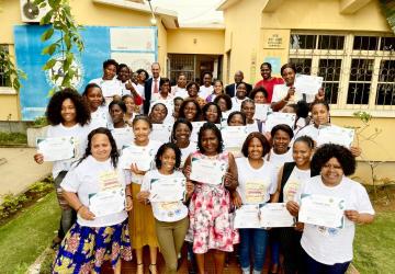 A large group of women hold up certificates