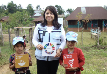 A woman holds a sign with two children.