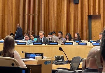 An image of several people in a meeting room with country signs displayed in front of each seat.