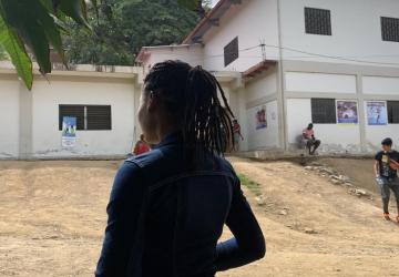 The silhouette of a young girl near a white building. 