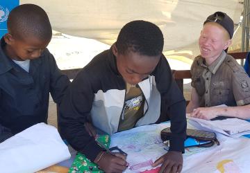 Three children drawing inside a tent