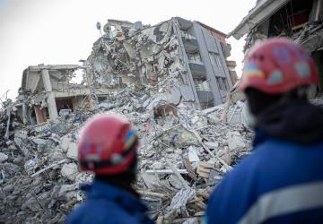 Two rescue workers look onto a destroyed building