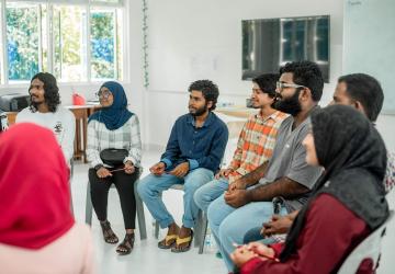 group of young people sit in circle speaking 