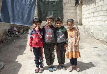 Group of four children stand together smiling 