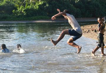 young boys jump into a river 