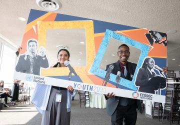 a young man and woman stand posing with posters 