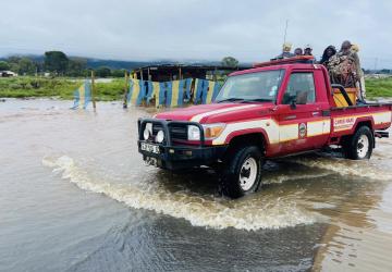 a red truck driving along a flooded road 