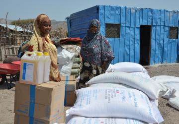 a woman and man stand with boxes and sacks of food 