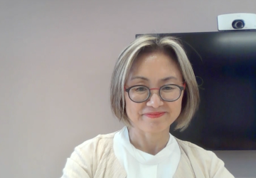 woman in white top looks into the camera 