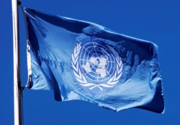 Blue UN flag against blue sky 