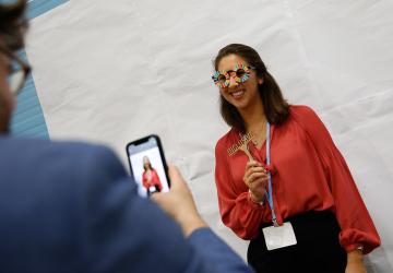 young woman in red shirt poses for a photo in SDG themed glasses