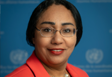 woman with dark hair and red jacket smiles to the camera 