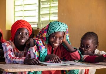 group of three young children sit next to one another and smile at the camera 