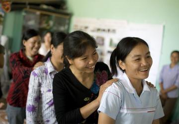 women standing in a line behind each other laugh and smile 