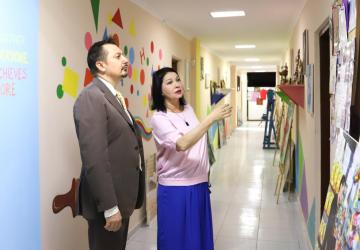 Gulya Choreklieva and Dmitry Shlapachenko stand in a hallway at the Yenme office in Ashgabat looking at materials on the walls. 