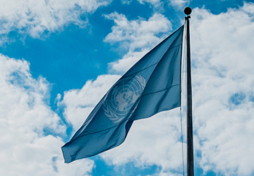 Blue UN flag against cloudy sky 
