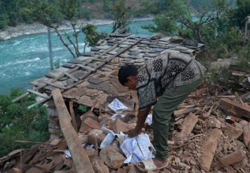 boy sifts through rubble of collapsed building