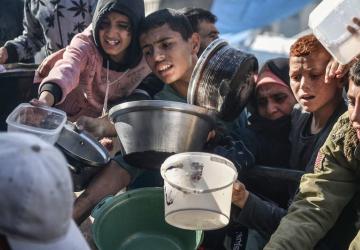A group of children in Gaza hold out empty bowls and cups