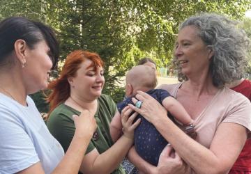 Denise Brown holding a baby while speaking to other women