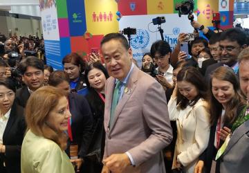 The RC and Thai PM are in a crowded and joyful scene, with media and young people surrounding them