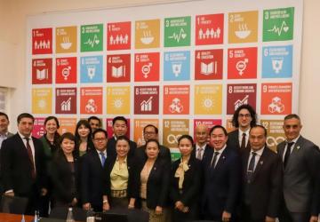 A group of people looking at the camera with the colourful SDG logos in the background 