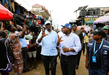 Two men walk through a rural market 