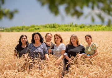 A group of women standing in a field and looking out at the camera 