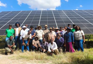 A group of people standing in front of a panel of solar panels 