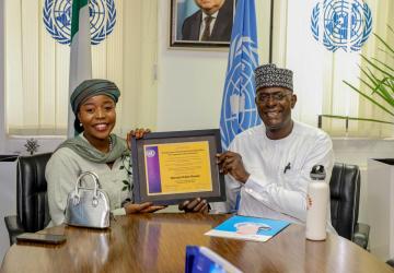 A man and a woman are looking at the camera and smiling they are holding an award between them