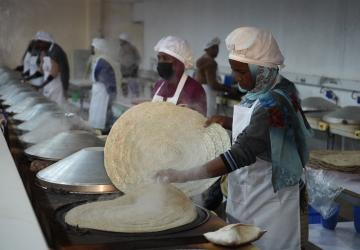 A group of women are cooking in a hot steaming room 