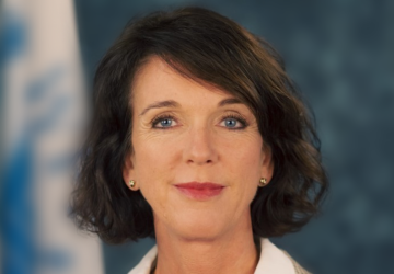 A photo of Arnhild Spence of Norway, in front of a blurred out UN flag