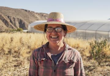 A female Chilean farmer stands on her land.