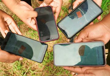 Several hands each hold a cell phone.