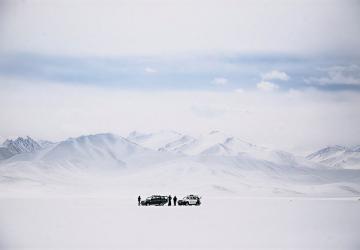 A group of people stand in front of a snowy mountain in Tajikistan.