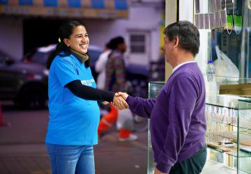 A female UN volunteer in Peru shakes hands with a local man. 