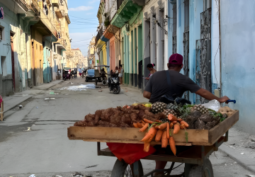 A man in Cuba rolls his fruit stand.