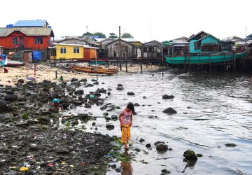 A girl in the Philippines walks near the coast.
