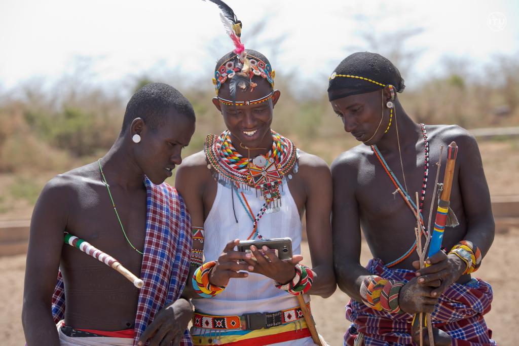 three men in traditional Kenyan dress look at mobile phone 