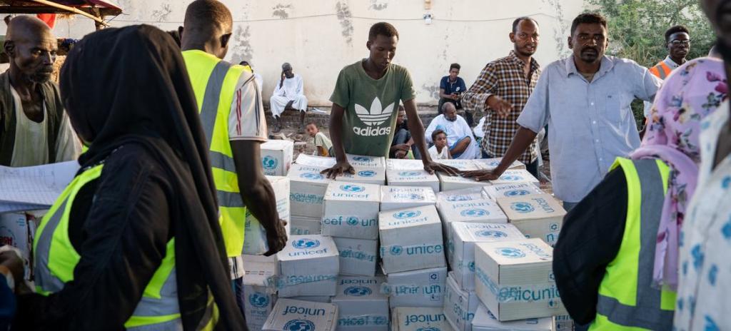 A group of people standing around boxes of supplies marked with UNICEF branding