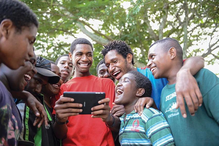 A group of young people gather around a digital tablet